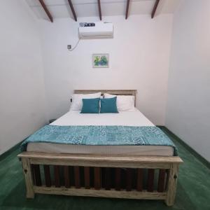 a bedroom with a bed with blue pillows at Shells By D in Negombo