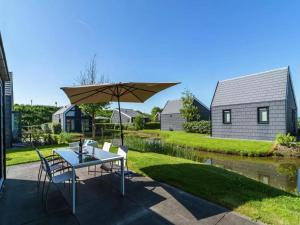 a patio with a table and chairs and an umbrella at Vogeltrek in Kattendijke