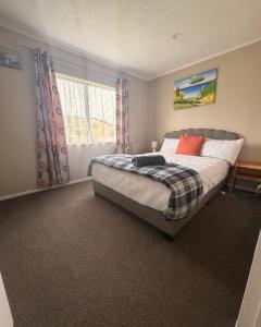 a bedroom with a bed and a window at Stylish Trentham Retreat in Upper Hutt