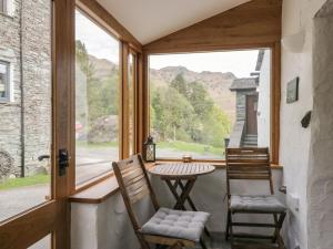 a porch with two chairs and a table and a window at Woodloft Cottage in Elterwater