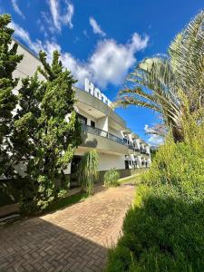 a white building with a palm tree in front of it at Imperial Hotel in Santa Bárbara