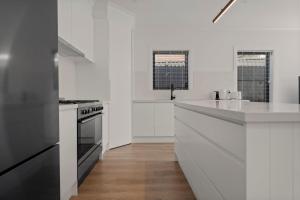 a white kitchen with white counters and a stove at Stylish & New 2 Bed & 2 Bath Apartment in Bathurst
