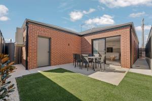 a brick building with a table and chairs on a patio at Stylish & New 2 Bed & 2 Bath Apartment in Bathurst