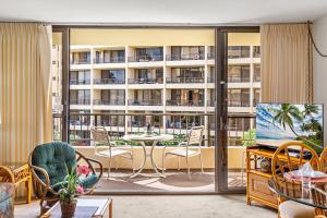 a living room with a balcony with a table and chairs at Sugar Beach 304 in Kihei
