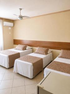 a room with three beds in a room with a ceiling at Imperial Hotel in Santa Bárbara