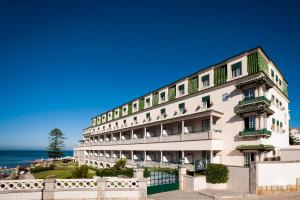a building on the beach with the ocean in the background at Vila Gale Ericeira in Ericeira