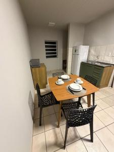 a kitchen with a wooden table and chairs in a room at Apto centro 03 in Tubarão