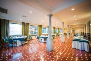a banquet hall with blue tables and chairs and windows at Vila Gale Ericeira in Ericeira