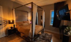 a bedroom with a canopy bed and a television at Master Suite De Carlo Shared Property PRIVATE stay NYC 18mins in North Bergen