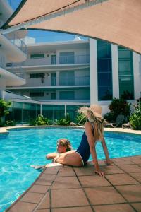 two women are laying in the swimming pool at Grand Palais Boolarong Beachside Apartments in Alexandra Headland