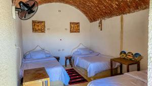 a room with two beds and a ceiling fan at Agmair Amellal in Siwa