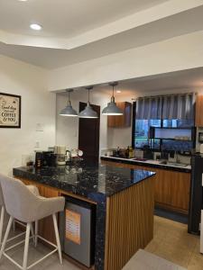 a kitchen with a large counter and a bar with chairs at Riverduplex - Luxury duplex at a fair price in Dauis