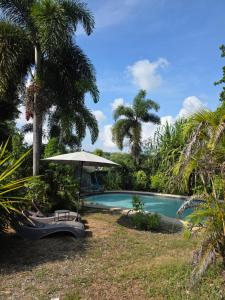 a swimming pool with an umbrella and a bench at Riverduplex - Luxury duplex at a fair price in Dauis