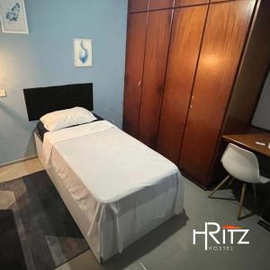 ein Schlafzimmer mit einem Bett und einem Holzschrank in der Unterkunft Ritz Hostel in Araçatuba