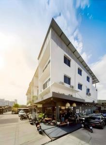 a large white building with cars parked in a parking lot at Youyen Hostel in Ban Don Muang (1)