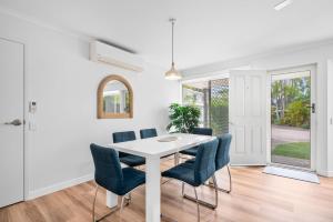 a white dining room with a white table and blue chairs at Renovated 2 Bedroom Ground Level Villa in Noosaville in Noosaville +12 photos