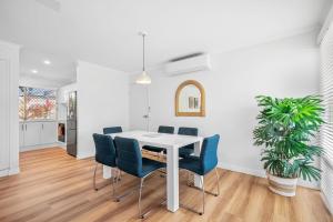 a dining room with a white table and blue chairs at Renovated 2 Bedroom Ground Level Villa in Noosaville in Noosaville