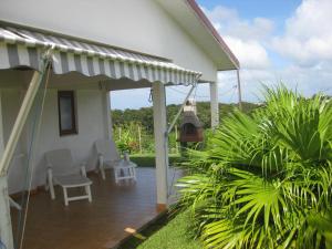 a white house with a porch with two chairs at Mon Repos in Sainte-Luce