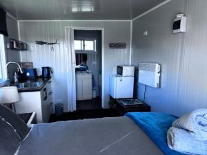 a small bedroom with a bed and a kitchen at Raglan Seaview Cabin in Raglan
