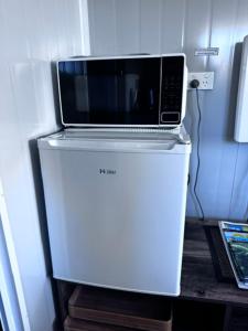 a microwave sitting on top of a refrigerator at Raglan Seaview Cabin in Raglan