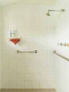a bathroom with a shower with white tiles at Artist's Beach House - Waterfront in Murdunna