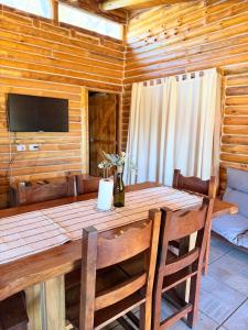a wooden dining room table with chairs and a television at Cabaña Manzano Historico Punta Negra Lodge 2 in Tunuyán