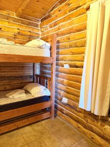 a room with two bunk beds in a log cabin at Cabaña Manzano Historico Punta Negra Lodge 2 in Tunuyán