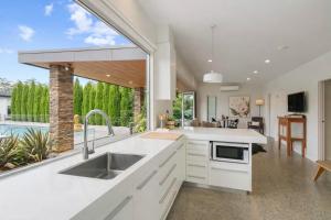 a kitchen with white cabinets and a large window at Modern Luxuries Guesthouse in Berowra