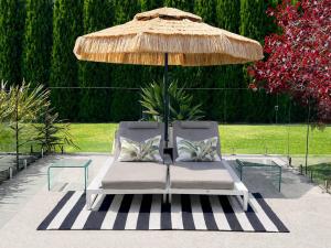 two lounge chairs under an umbrella on a patio at Modern Luxuries Guesthouse in Berowra