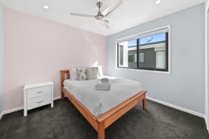 a white bedroom with a bed and a window at Sunshine Coast Escape | Beachside, Pool & Views in Kawana Waters +30 photos