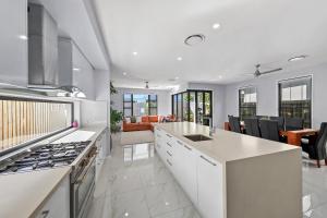 a kitchen with a stove and a living room at Sunshine Coast Escape | Beachside, Pool & Views in Kawana Waters