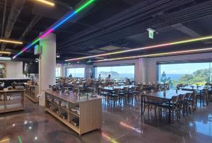 a dining room with tables and chairs and large windows at Heyy Seogwipo Hotel in Seogwipo