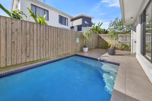a swimming pool in a backyard with a wooden fence at Sunshine Coast Escape | Beachside, Pool & Views in Kawana Waters