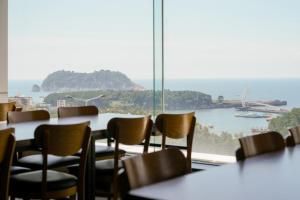 a room with tables and chairs and a large window at Heyy Seogwipo Hotel in Seogwipo