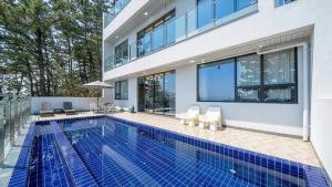 a swimming pool in front of a house at Yeongdeok Full Moon Pool Villa in Yŏngdŏk