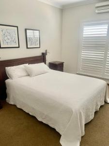 a bedroom with a large white bed and a window at Mudgee Gardens Stayz in Mudgee