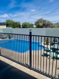 a fence with a swimming pool behind it at Mudgee Gardens Stayz in Mudgee +18 photos