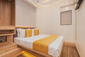 a bedroom with a large bed with yellow pillows at Hotel Lexus7 in Mumbai