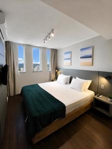 a bedroom with a large white bed with windows at Apartamento Vista Ponte in Niterói