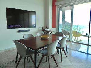a dining room with a table and chairs and a tv at B Esmeralda Pichilingue PentHouse in Acapulco