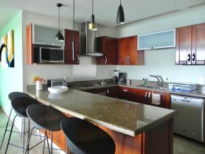 a kitchen with wooden cabinets and a counter with bar stools at B Esmeralda Pichilingue PentHouse in Acapulco