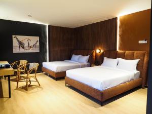 a hotel room with two beds and a table and chairs at Bonbon Hotel in Kluang