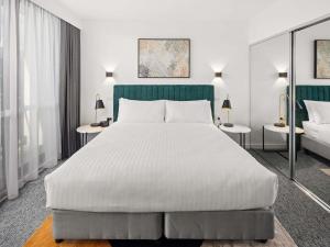 a bedroom with a large white bed and two tables at The Sebel Canberra Campbell in Canberra