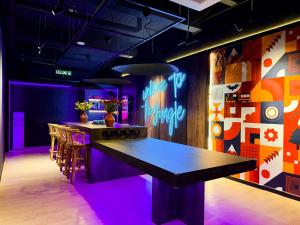 a bar in a room with purple lighting at Bonbon Hotel in Kluang