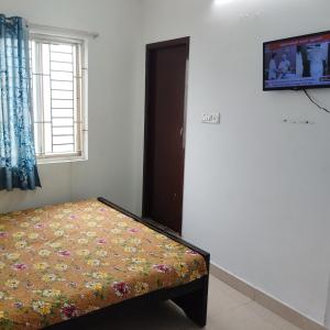 a bedroom with a bed and a tv on a wall at Shifa Home Near Apollo Sankara Nethralaya Main Hospital in Chennai