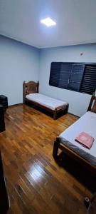 a room with two beds and a wooden floor at Casa Próxima ao Parque do Peão in Barretos
