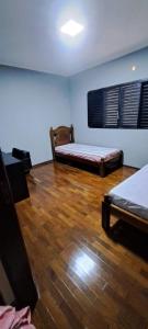 a room with two beds and a wooden floor at Casa Próxima ao Parque do Peão in Barretos +8 photos