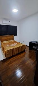 a bed in a room with a wooden floor at Casa Próxima ao Parque do Peão in Barretos