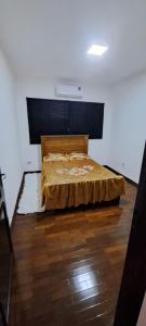 a bedroom with a bed and a wooden floor at Casa Próxima ao Parque do Peão in Barretos