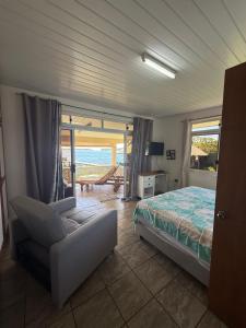 a bedroom with a bed and a chair and a balcony at Fare Holidays - Raiatea in Taputapuapea